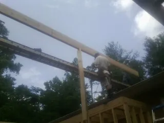 Carpenter setting a ridge beam over a new addition frame — Ice Dam Removal by Roofing Brothers in Larchwood
