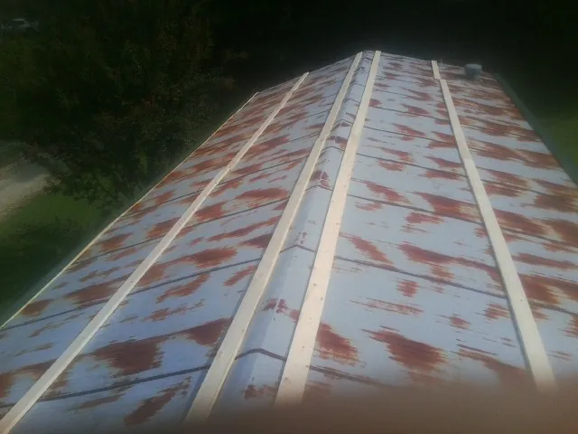 Rusted metal roof panels with new wood purlins before replacement — Storm Damage Roof Repair in Larchwood by Roofing Brothers