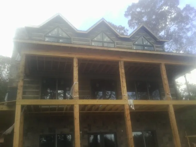 Dormers and porch framing on a large log home under construction — Roof Coating work by our crew in Larchwood