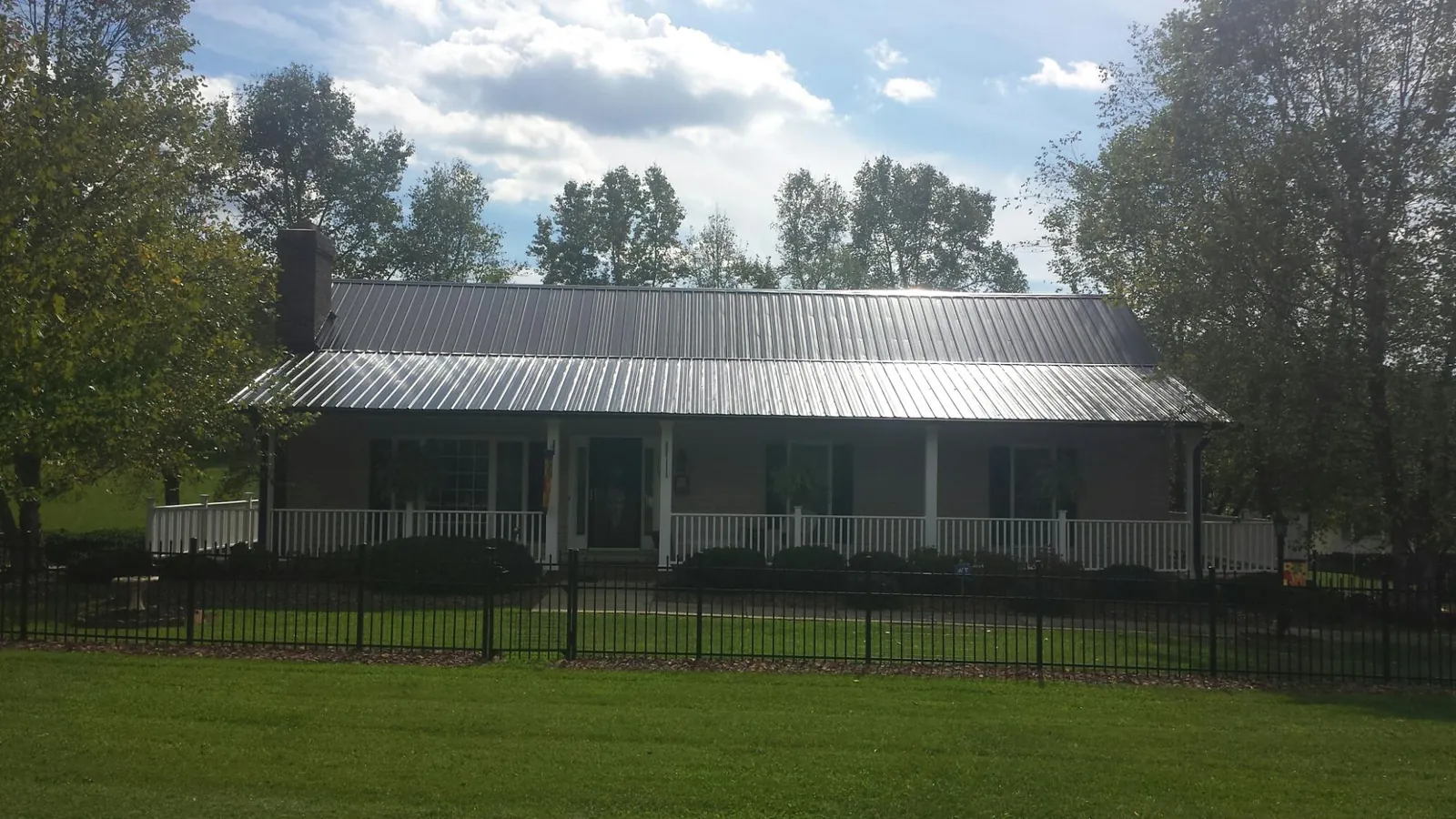 Gray metal roof on a brick ranch with a full width front porch — Gutter Guard Installation work by our crew in Larchwood