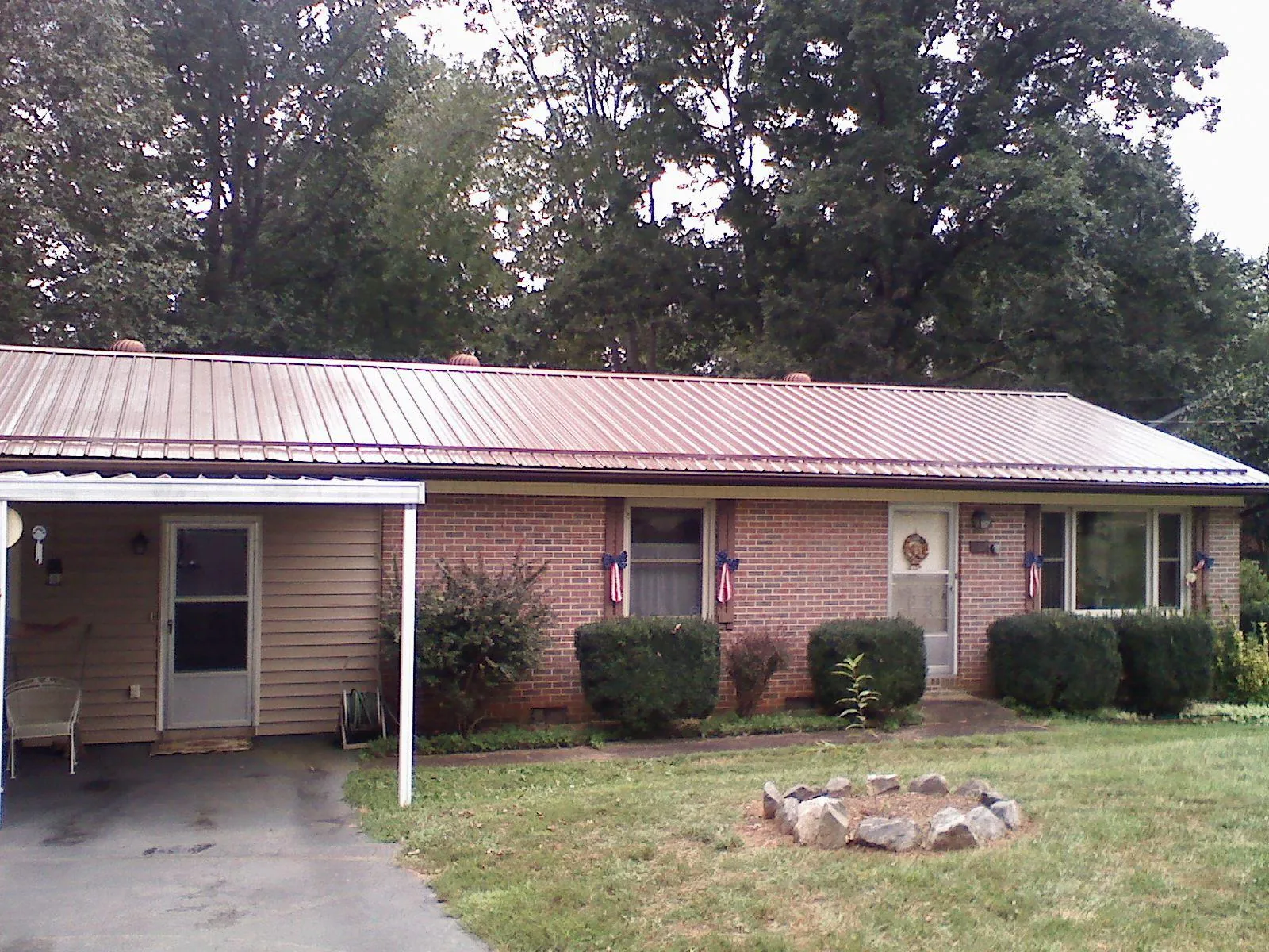 Bronze metal roof and carport on a brick ranch home — Roof Repair work by our crew in Larchwood