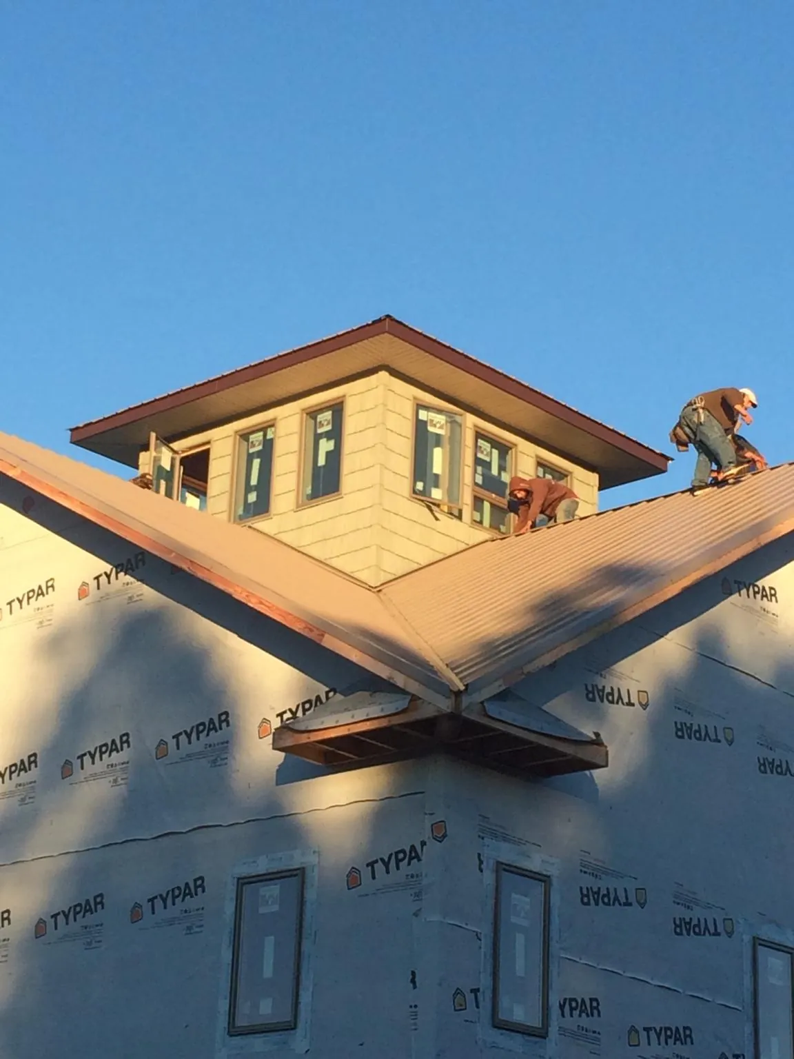 Roofers working around a rooftop cupola on a new metal roof at sunset — Roof Waterproofing in Larchwood by Roofing Brothers